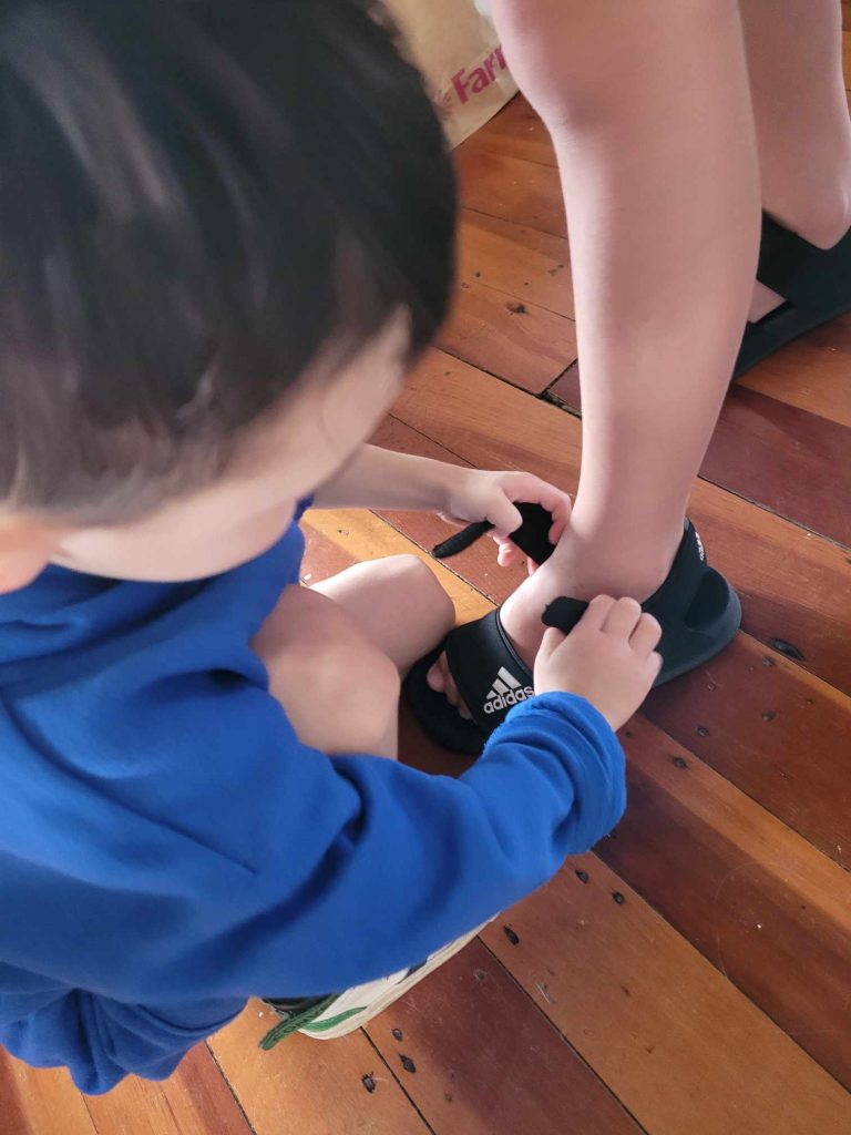 The Middle Child, Rahim, Helping The Oldest Child (with GDD) with his Shoes.